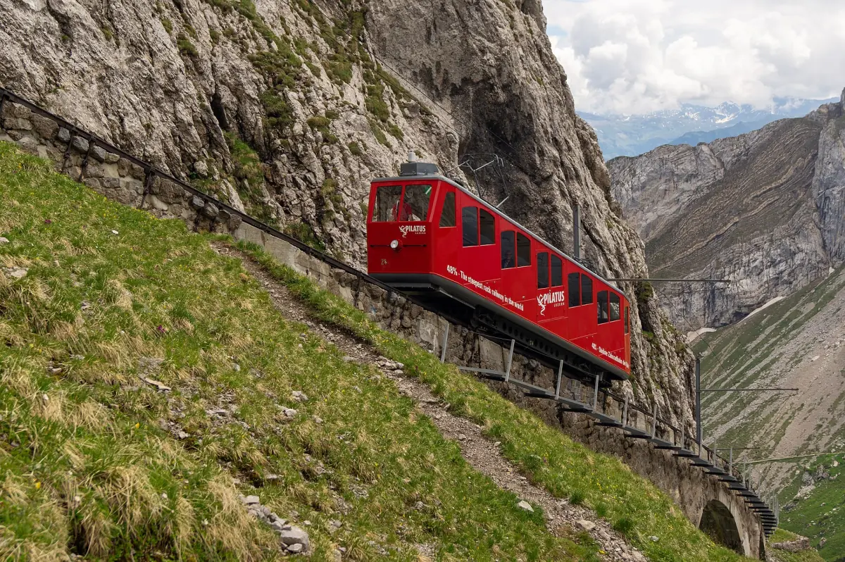 A red train of the Pilatus cogwheel railway climbing the steep rock face