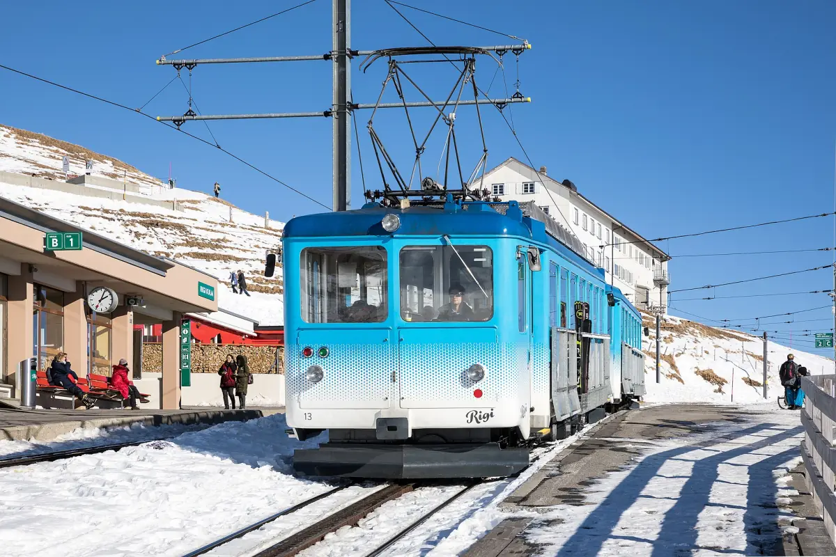 A blue Rigi railway train at Rigi Kulm station in winter